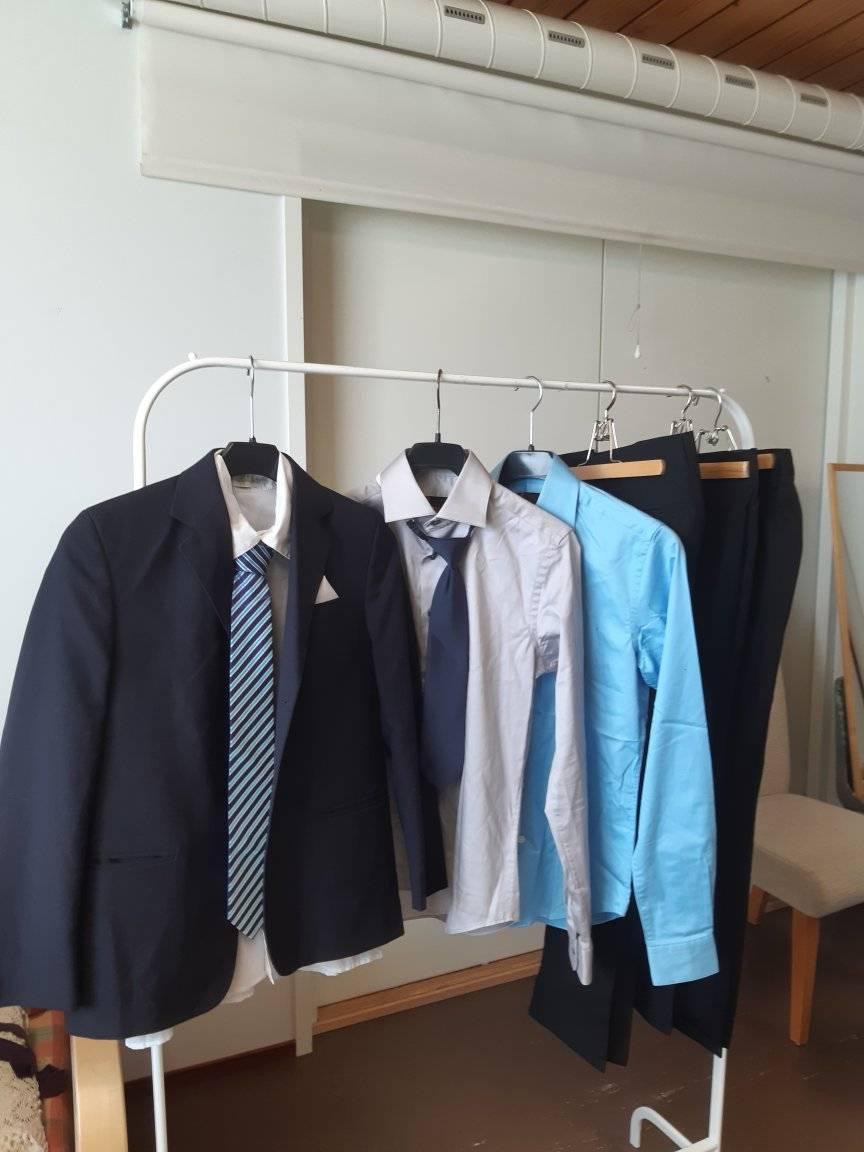Vaaterekissä miesten vaatteita: puvun takki ja sen alla paita, sekä muita miesten paitoja