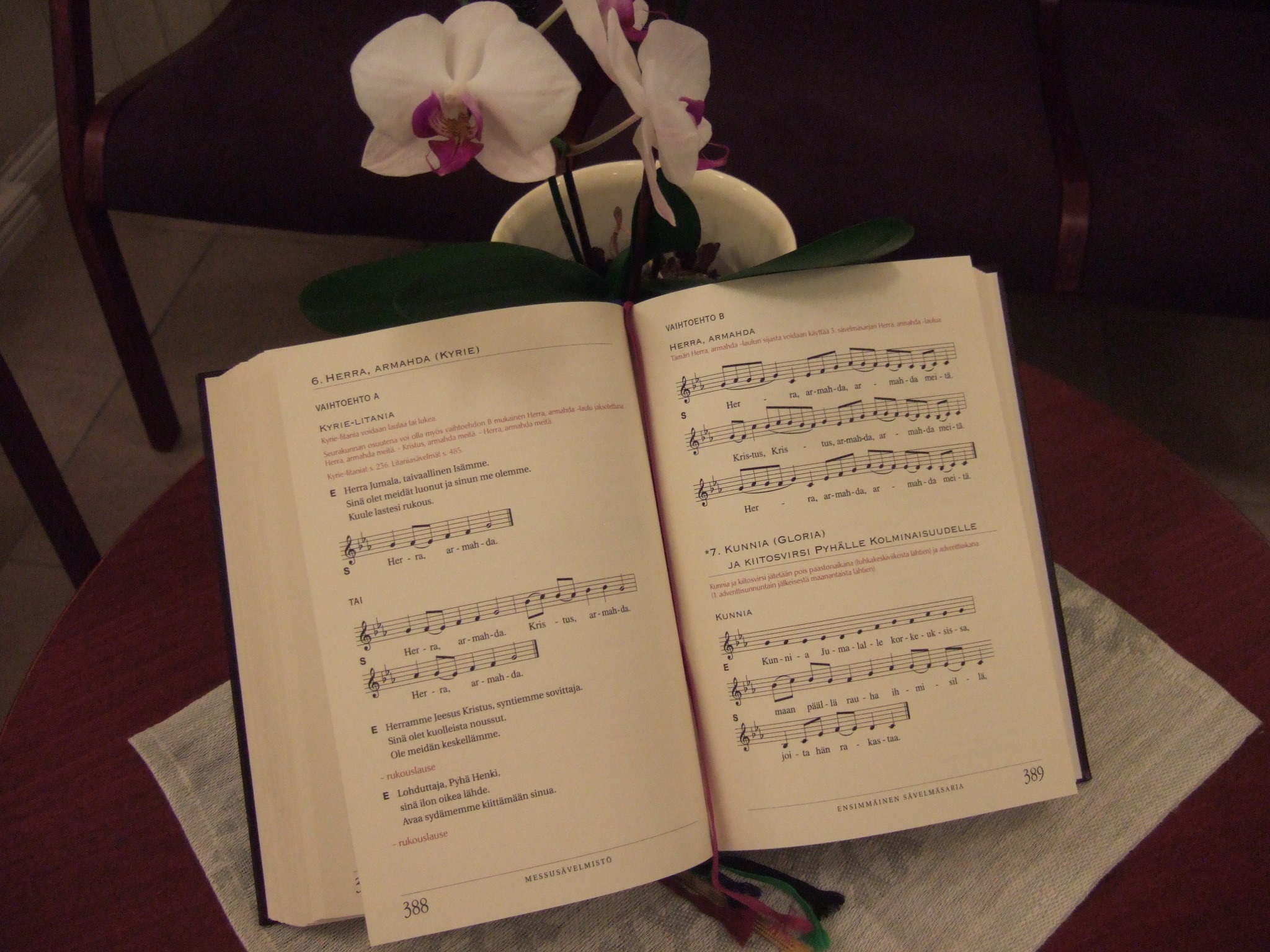 kuvassa orkideaa vasten nojallaan avoin virsikirja