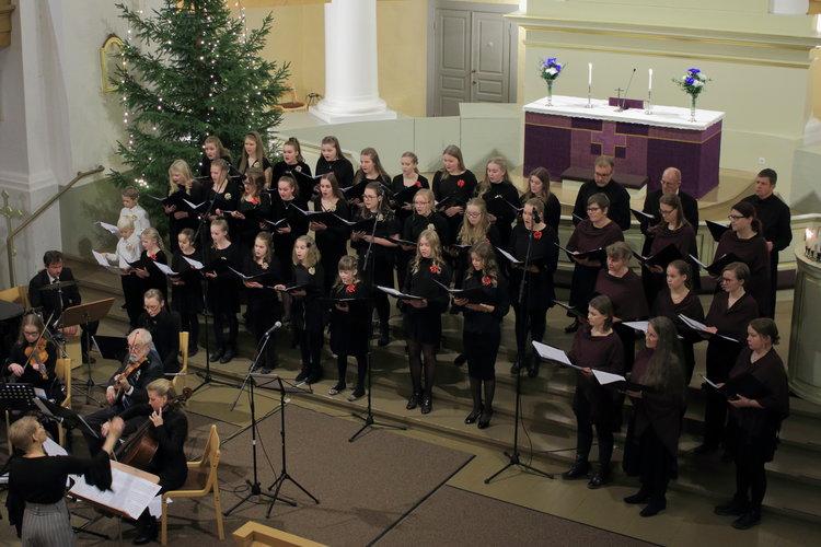 Nuorisokuoro laulamassa kirkossa jouluna, etualalla viulisteja